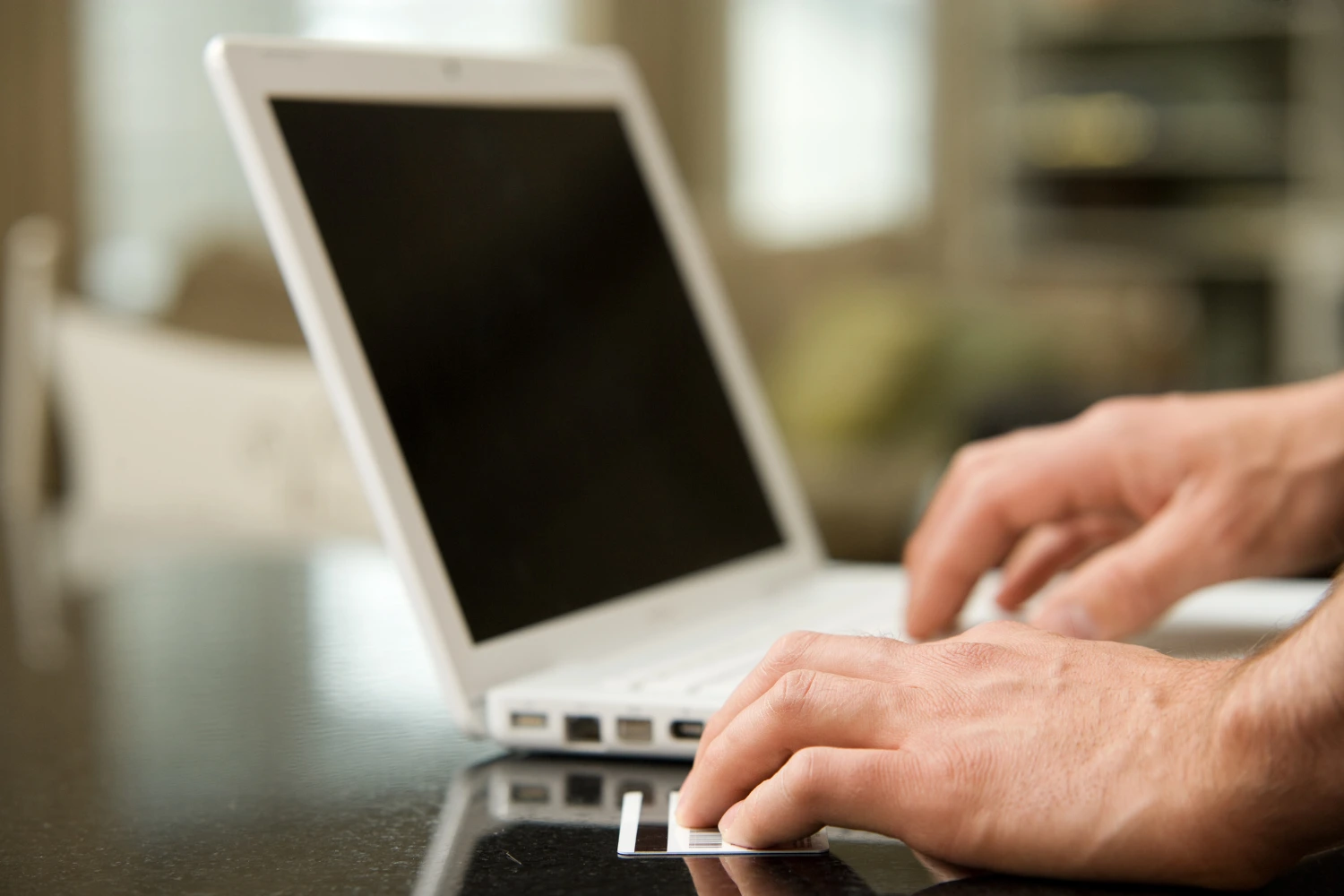 Lähikuva läppäri ja pankkikortti kädessä